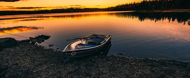 Rowing boat bobs at the water's edge at Ørsjøen at sunset