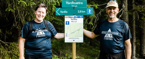 Two trail buddies stand by hiking signs