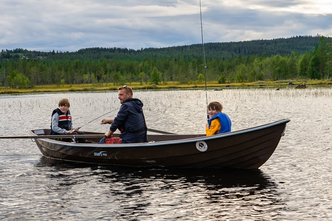 Father and two sons fishing from a rowing boat