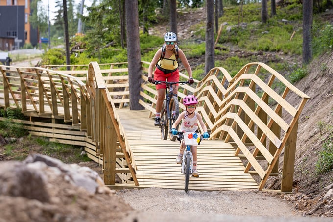 Lady and girl cycling over wooden bridge