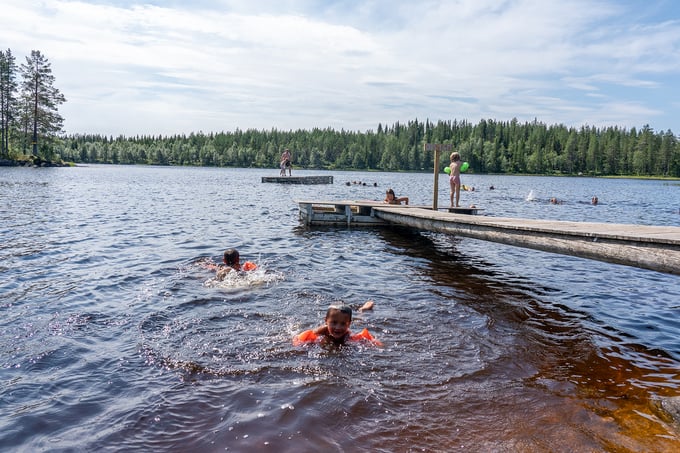 Two little boys swimming in lake at a bathing pier