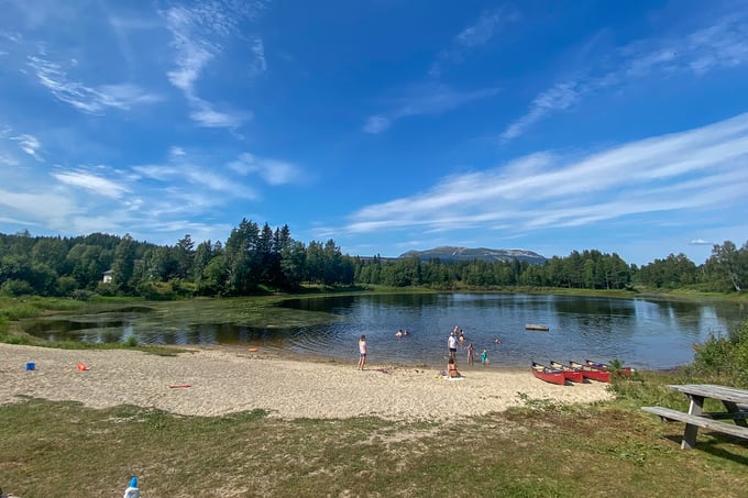 Overview of the bathing area Tjønna, with sandy beach, canoes and benches