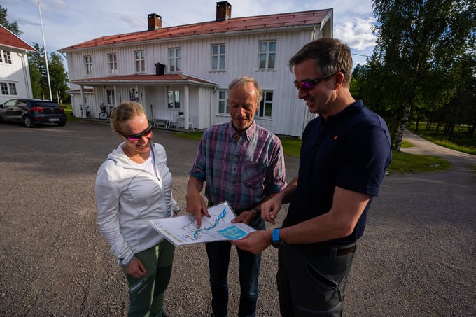 Fishing guide points to maps and talks to two guests in the yard