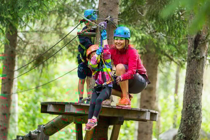 Mother helps daughter off on zipline in climbing park